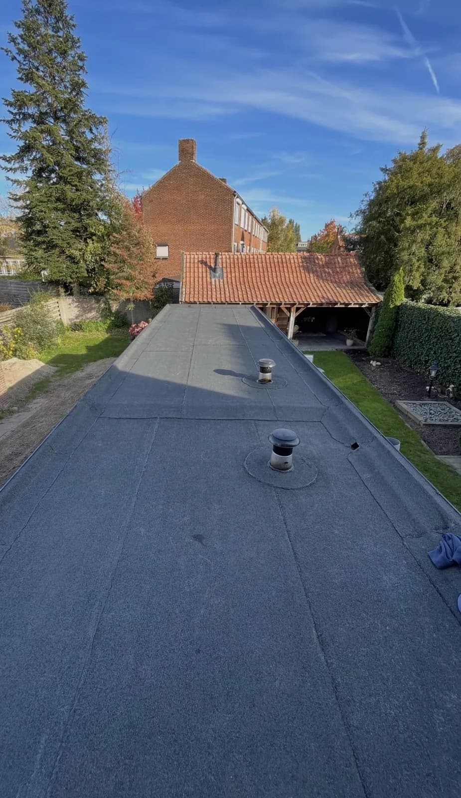 Nieuw grijs bitumen plat dak met twee ontluchtingskappen, gezien van bovenaf