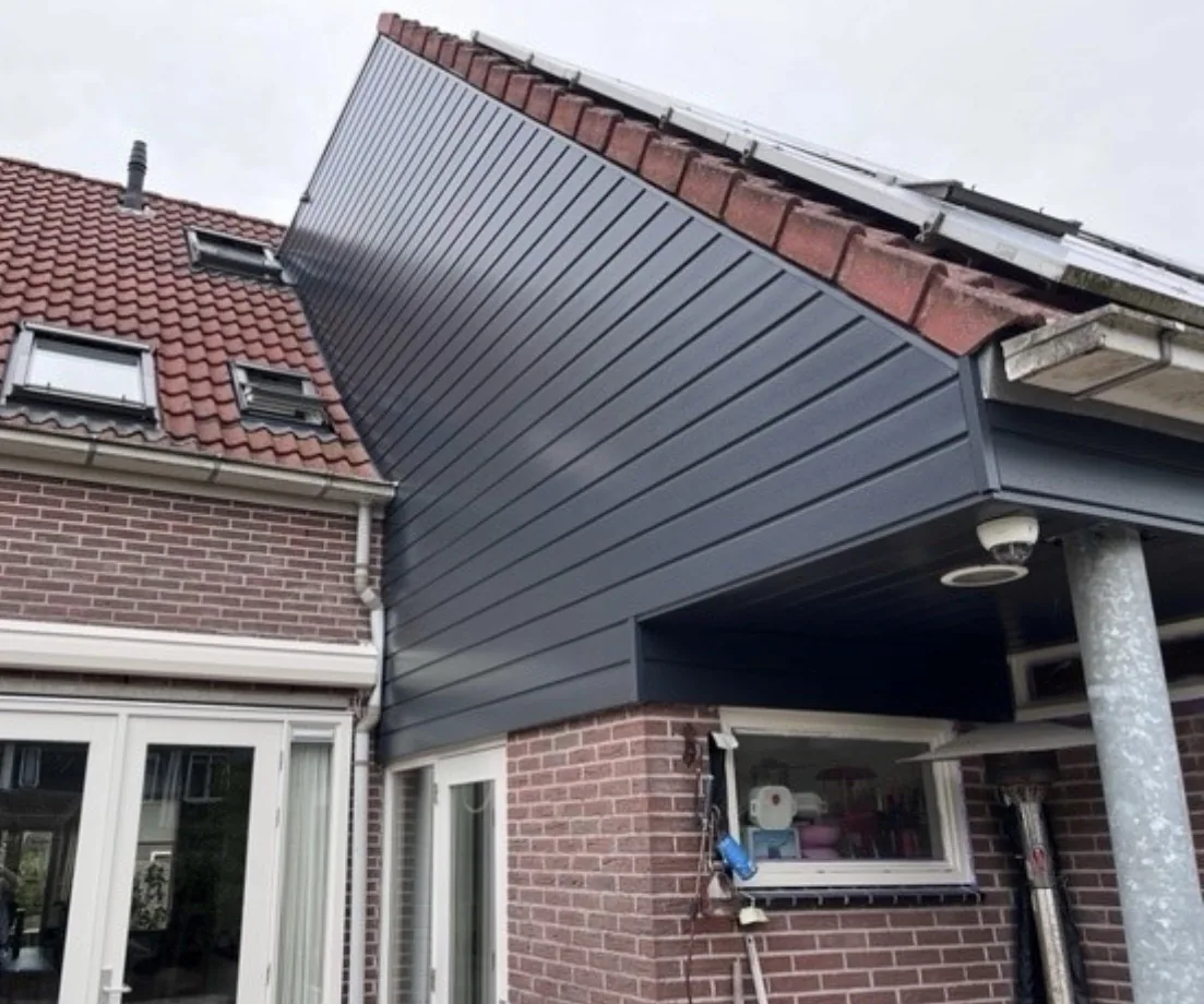 Overstek en boeideel met antraciet gevelbekleding naast een pannendak met zonnepanelen