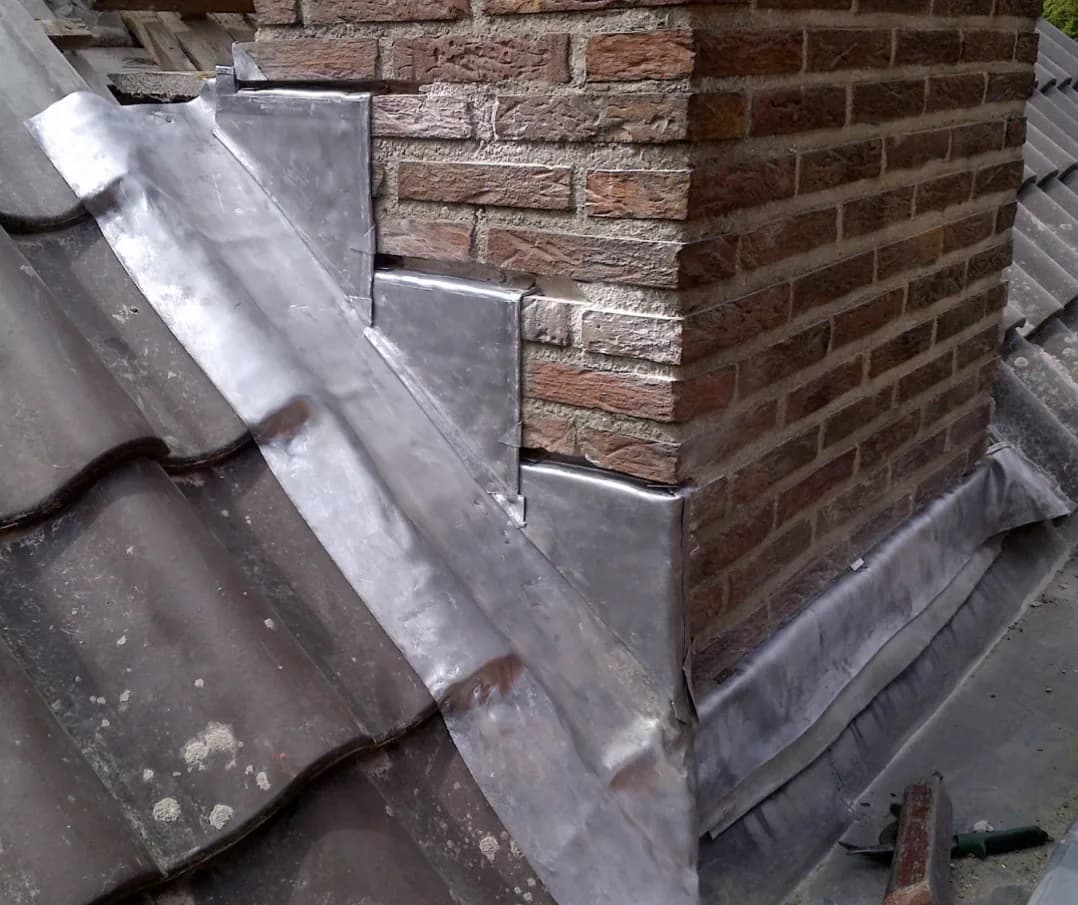 Pannendak met nieuw loodwerk rond een bakstenen schoorsteen