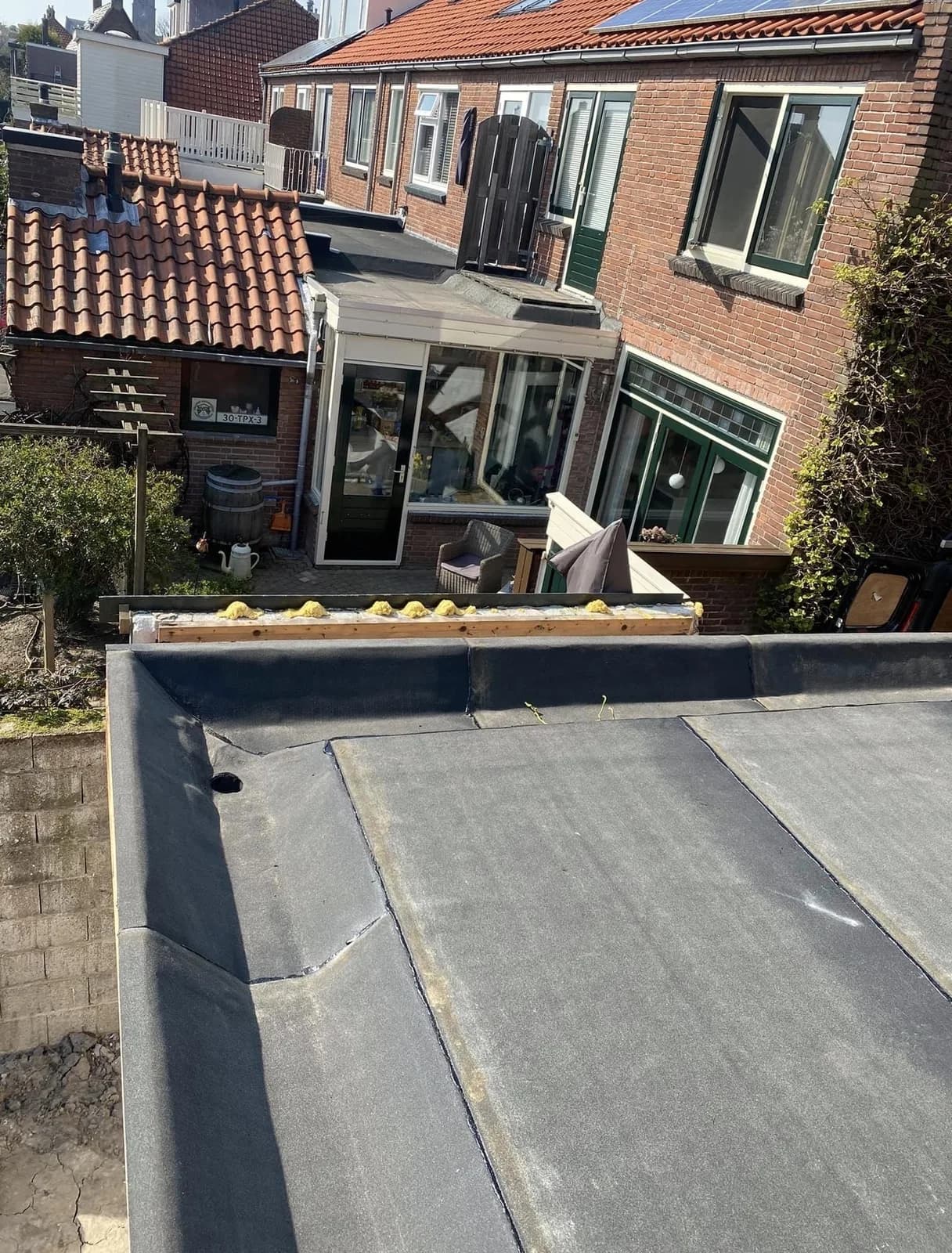 Nieuw zwart bitumen dak op een aanbouw met geïsoleerde opstand
